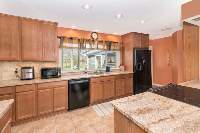 kitchen with brown cabinetry, black appliances, decorative backsplash, and a sink