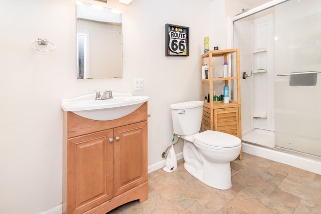 full bath featuring toilet, baseboards, stone finish flooring, a shower stall, and vanity
