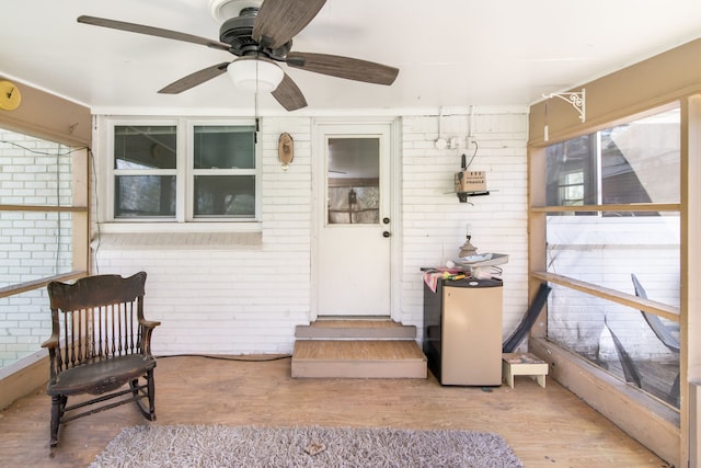 entrance to property with ceiling fan and brick siding