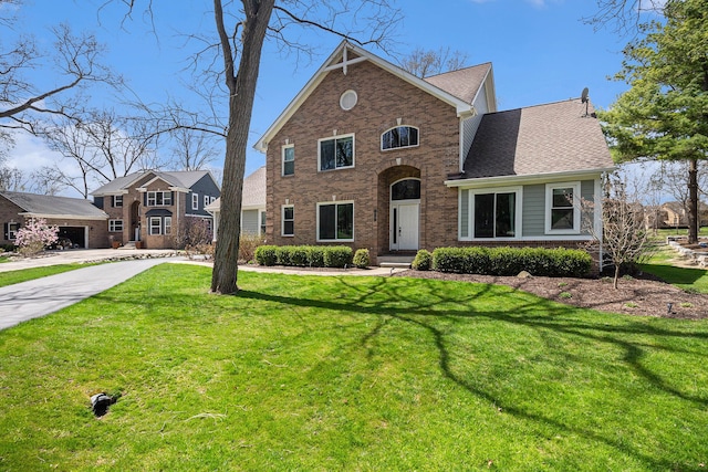 traditional-style house with concrete driveway, brick siding, and a front yard