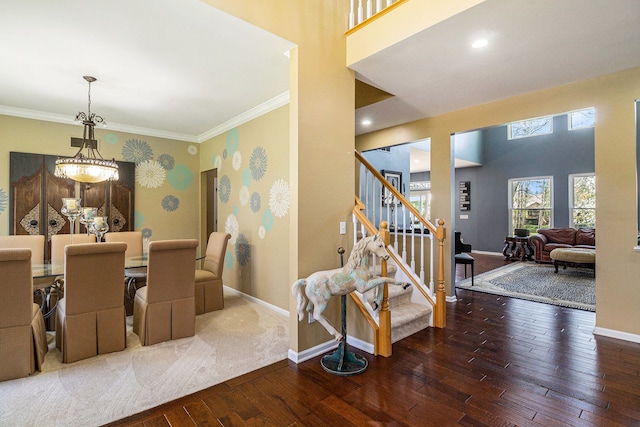 dining area with hardwood / wood-style flooring, baseboards, an inviting chandelier, ornamental molding, and stairs