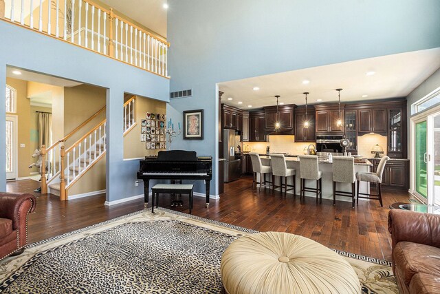 living room with stairway, baseboards, dark wood finished floors, and visible vents