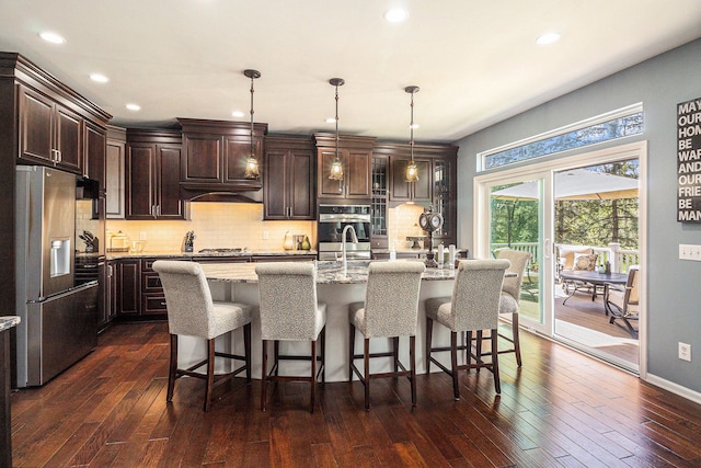 kitchen featuring light stone counters, backsplash, stainless steel appliances, and dark brown cabinetry