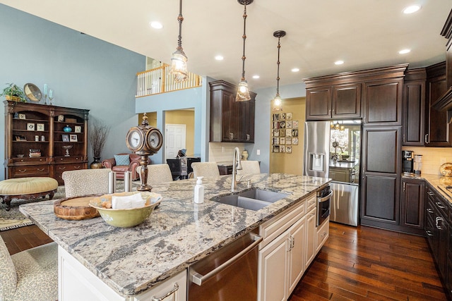 kitchen with stainless steel dishwasher, dark brown cabinetry, tasteful backsplash, light stone counters, and a sink