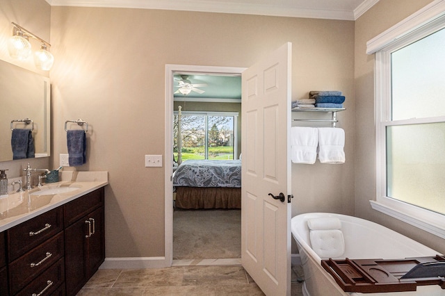 ensuite bathroom featuring vanity, ornamental molding, plenty of natural light, and a freestanding bath