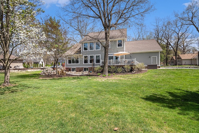 rear view of house featuring a lawn and a wooden deck