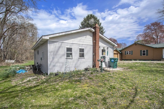 view of side of home with a lawn and a chimney