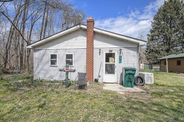 rear view of house featuring a yard, a chimney, and fence