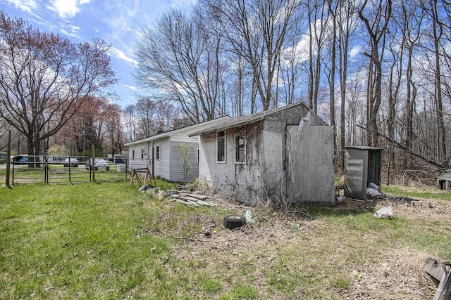view of property exterior with a gate, a yard, and fence