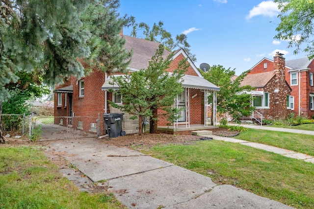 bungalow with driveway, a gate, covered porch, a front yard, and brick siding