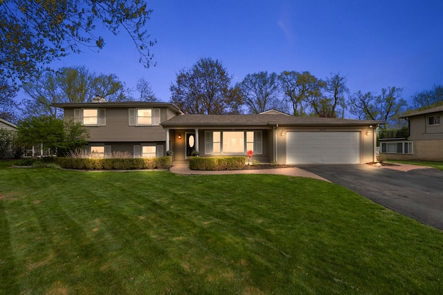 tri-level home featuring a garage, a front lawn, and aphalt driveway