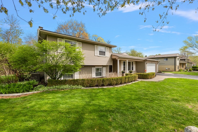 tri-level home with an attached garage, aphalt driveway, a chimney, and a front yard