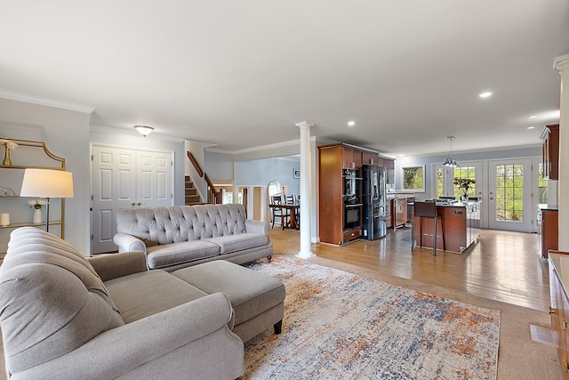 living room with crown molding, decorative columns, stairs, light wood-style floors, and recessed lighting