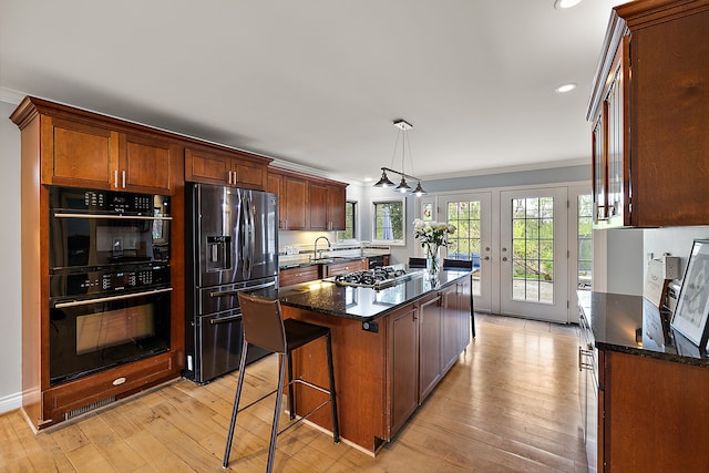 kitchen featuring dobule oven black, a center island, stainless steel fridge with ice dispenser, light wood-style floors, and dark stone counters