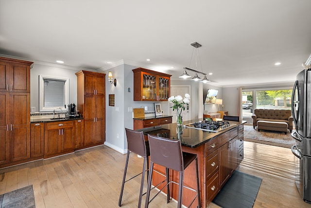 kitchen featuring crown molding, a breakfast bar, light wood-style flooring, stainless steel appliances, and open floor plan