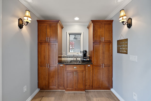 bar with baseboards, ornamental molding, and light wood finished floors