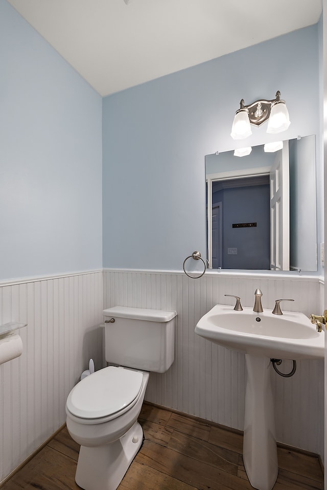 bathroom featuring wood-type flooring, toilet, and a wainscoted wall