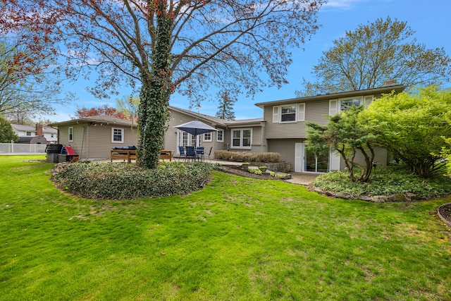 rear view of house featuring a lawn, fence, a chimney, and a patio area