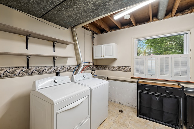 laundry room featuring cabinet space, light tile patterned floors, and washing machine and clothes dryer