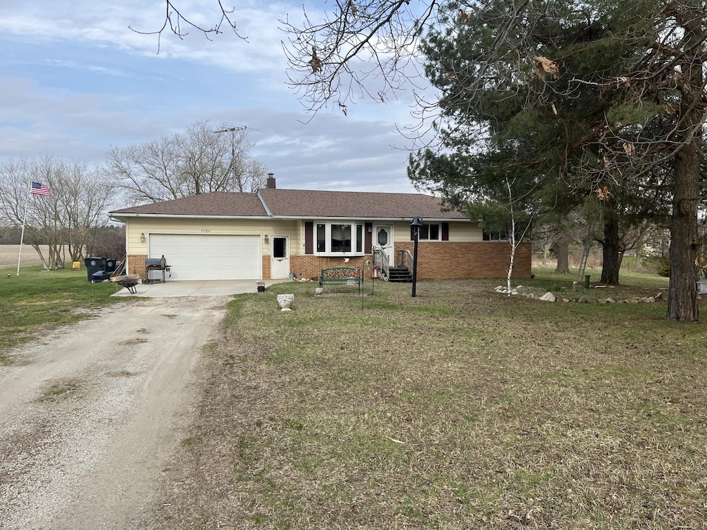 ranch-style house featuring brick siding, dirt driveway, an attached garage, and a front yard