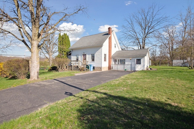 exterior space featuring a lawn, a chimney, and driveway