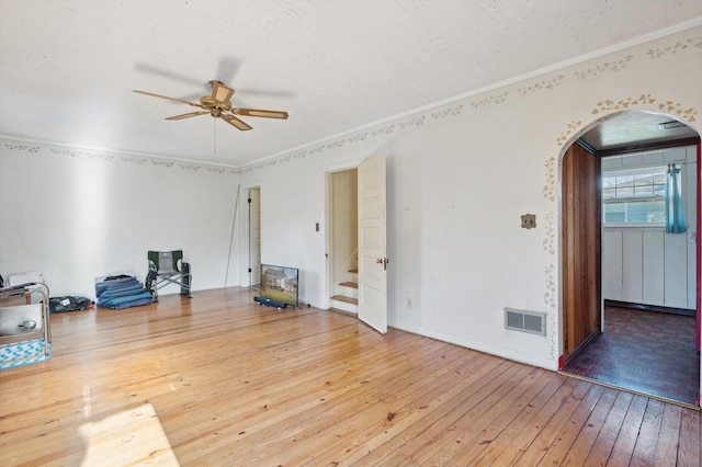 unfurnished room featuring hardwood / wood-style floors, ceiling fan, arched walkways, ornamental molding, and visible vents