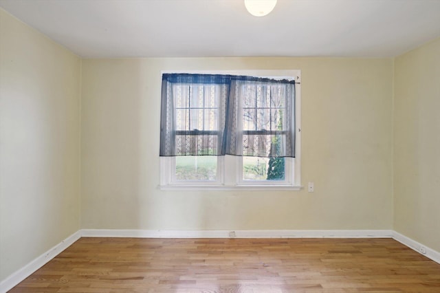 spare room with plenty of natural light, baseboards, and wood finished floors