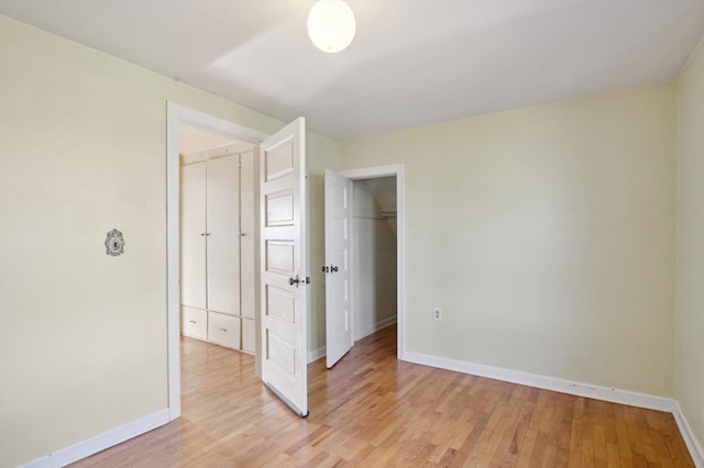 unfurnished bedroom featuring light wood-style flooring, baseboards, and a closet