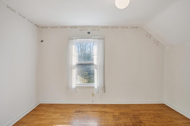 additional living space with vaulted ceiling, light wood-style floors, and baseboards