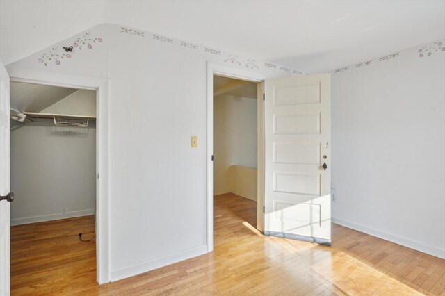 unfurnished bedroom featuring light wood-type flooring, baseboards, and a closet