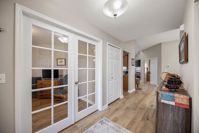 doorway featuring french doors, baseboards, and light wood-style flooring