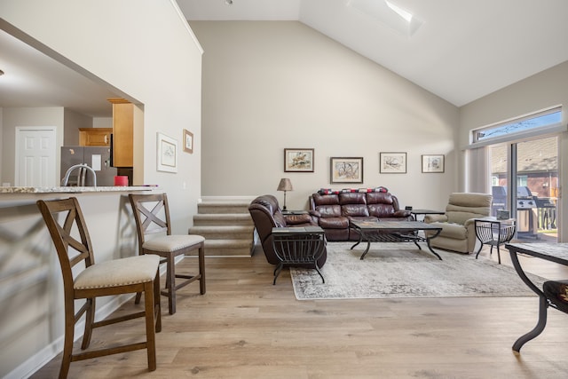 living room featuring light wood-style flooring, high vaulted ceiling, and stairs