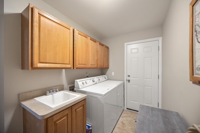 laundry room featuring washing machine and dryer, cabinet space, and a sink