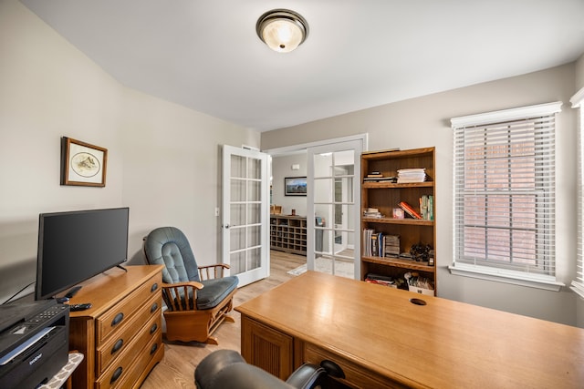 office with light wood-style floors and french doors