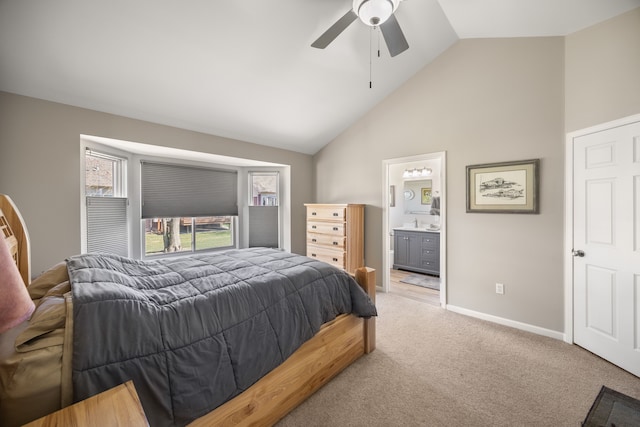 bedroom featuring a ceiling fan, light colored carpet, baseboards, high vaulted ceiling, and ensuite bathroom