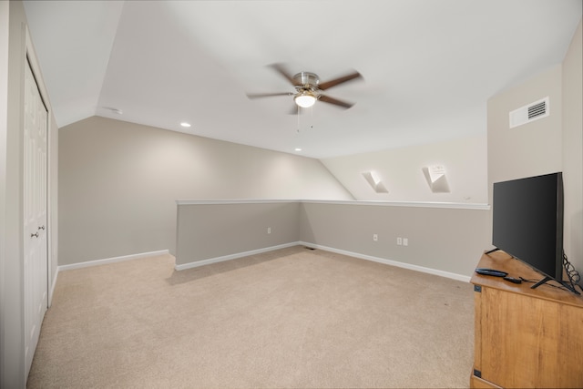 additional living space featuring vaulted ceiling, visible vents, a ceiling fan, and light colored carpet