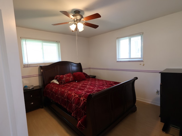 bedroom featuring light wood-style floors, multiple windows, and a ceiling fan