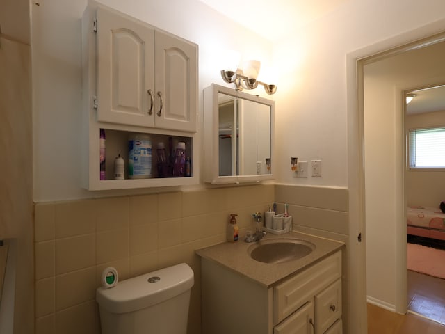 half bath with vanity, toilet, and tile walls