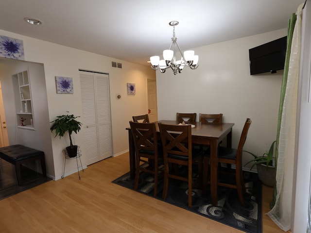 dining room with visible vents, light wood-style flooring, baseboards, and a notable chandelier