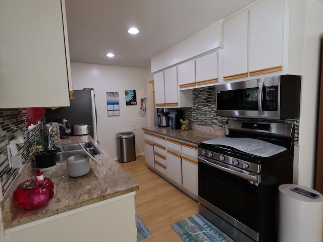 kitchen with a sink, tasteful backsplash, light wood-style floors, and stainless steel appliances