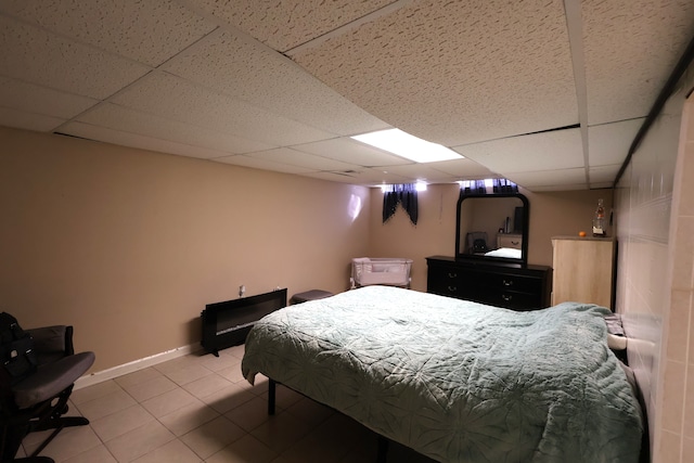 tiled bedroom featuring baseboards and a drop ceiling