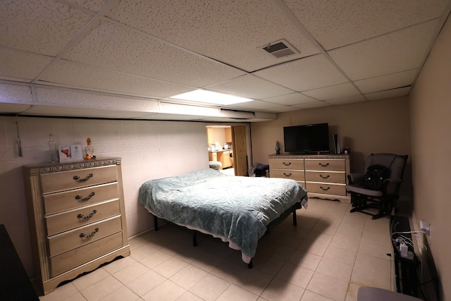 bedroom featuring light tile patterned floors, a paneled ceiling, and visible vents
