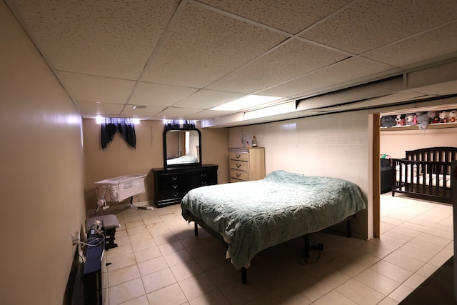 bedroom with light tile patterned floors and a drop ceiling