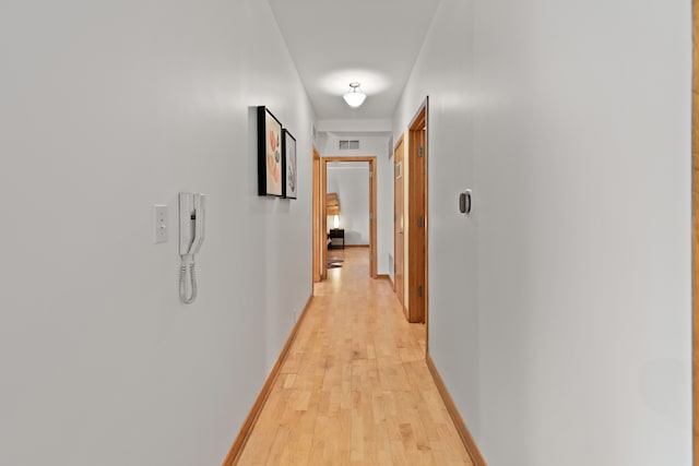 corridor featuring baseboards, visible vents, and light wood-style flooring