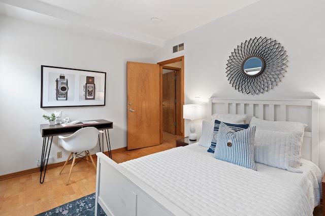 bedroom with wood finished floors, visible vents, and baseboards