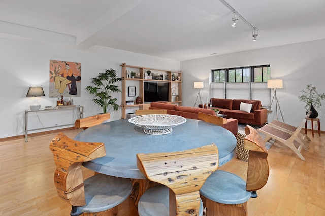 dining area featuring track lighting, light wood-type flooring, beamed ceiling, and baseboards