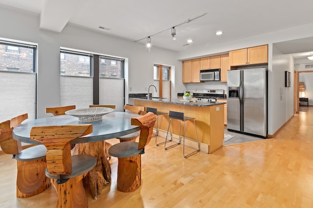 kitchen featuring a sink, appliances with stainless steel finishes, visible vents, light brown cabinets, and light wood-style floors