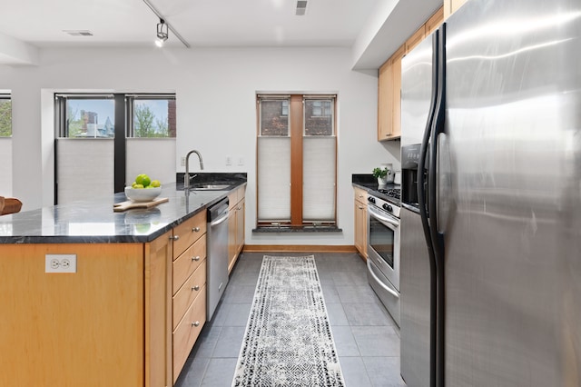 kitchen featuring dark stone counters, appliances with stainless steel finishes, a sink, visible vents, and a peninsula