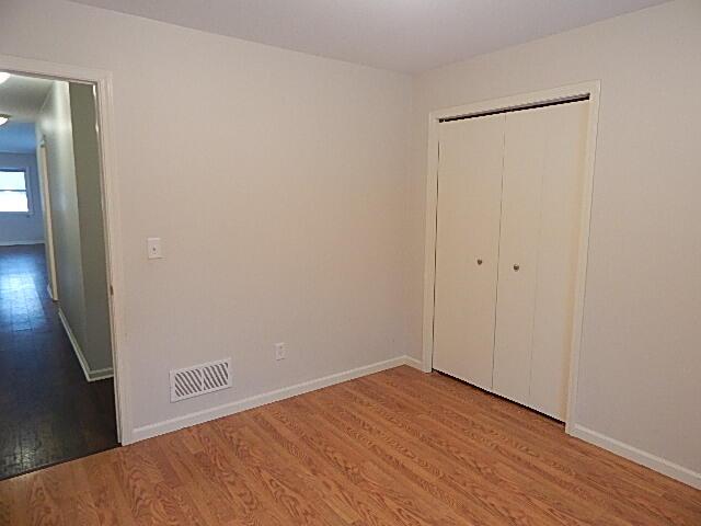 unfurnished bedroom featuring wood finished floors, baseboards, and a closet