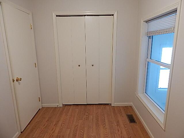 unfurnished bedroom featuring light wood-style flooring, a closet, and baseboards